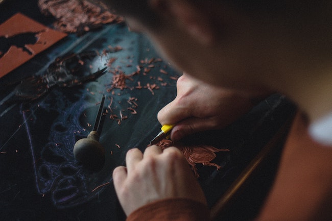small boy carving images into wood