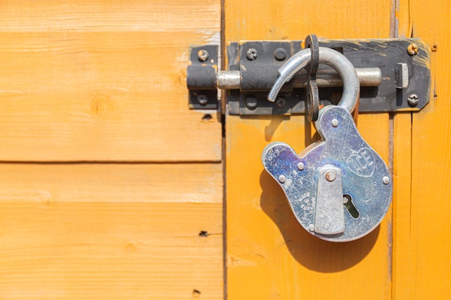 unlocked lock hanging from a latched door