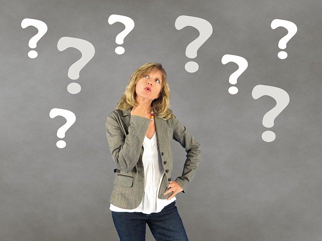 woman against blackboard with questions marks floating above her