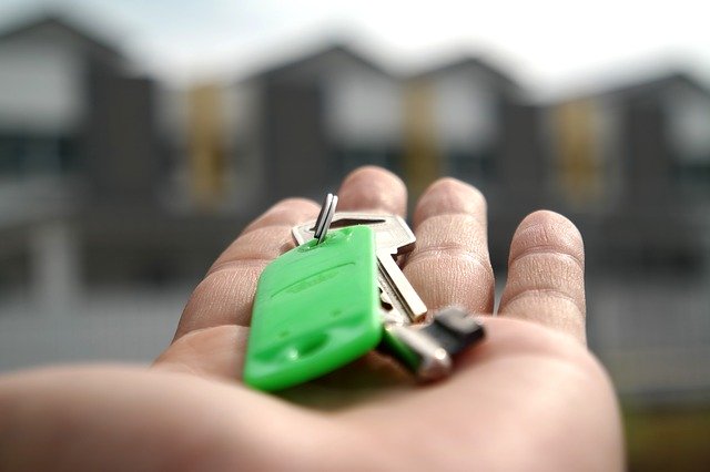 open hand with keys in palm in front of 4 properties.