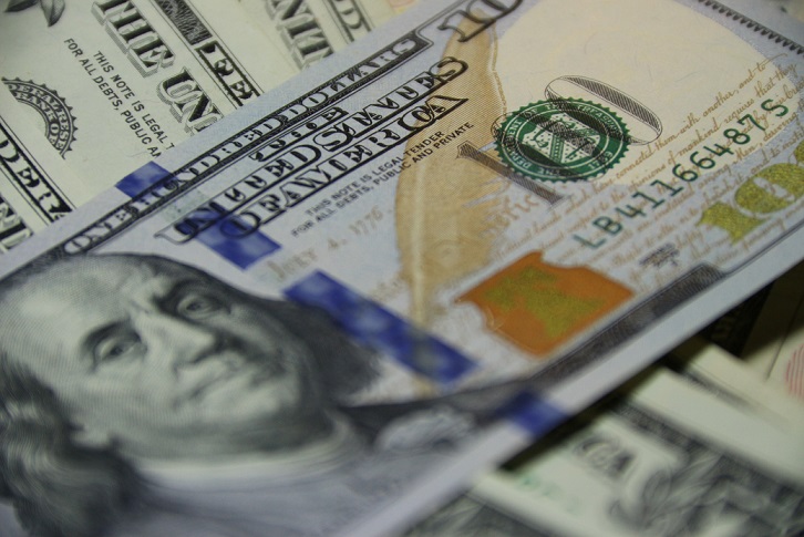 close up of a 100 dollar bill upon a stack of other bills