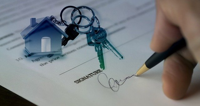 signing name under form where a house keychain and keys are