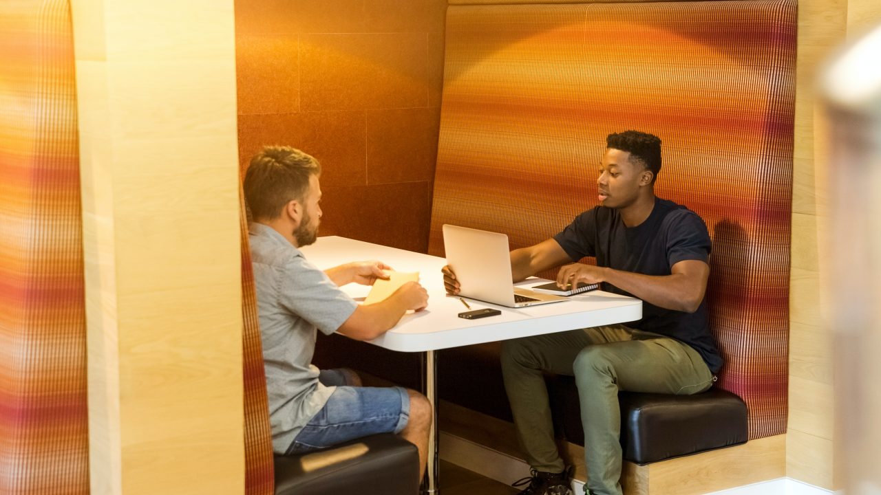 two entrepreneurs sitting at a table with laptop open