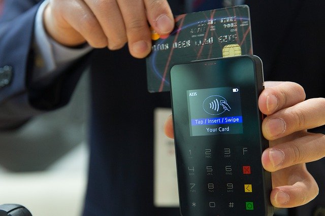 a hand swiping a credit card through a phone terminal