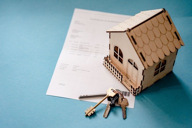 small bird house with keys atop a paper contract