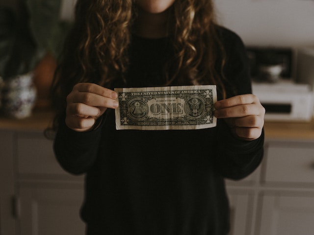 young girl holding a US dollar bill