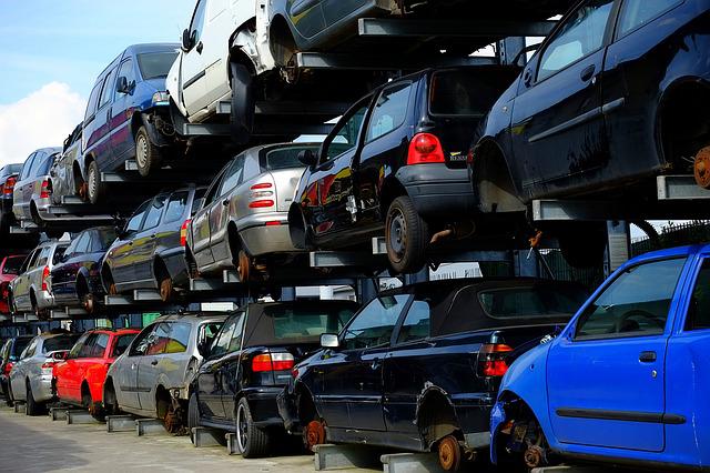 junkyard of new cars stacked atop one another