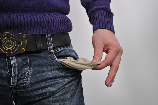 mid-shot of a man’s torso pulling out the inside of his pant’s pocket revealing that they’re empty inside