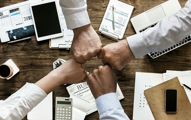 a team of four putting their fists together in comradery