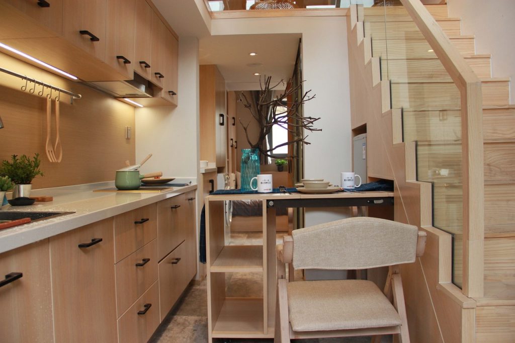 hallway with a pullout kitchenette nearby a stairway and kitchen counter