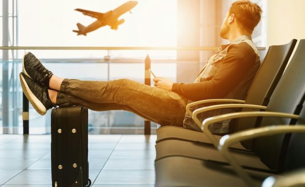 a person sitting with their legs crossed over their luggage in an airport