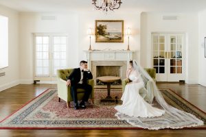 a groom and bride sitting in opposite chairs staring thoughtfully at each other