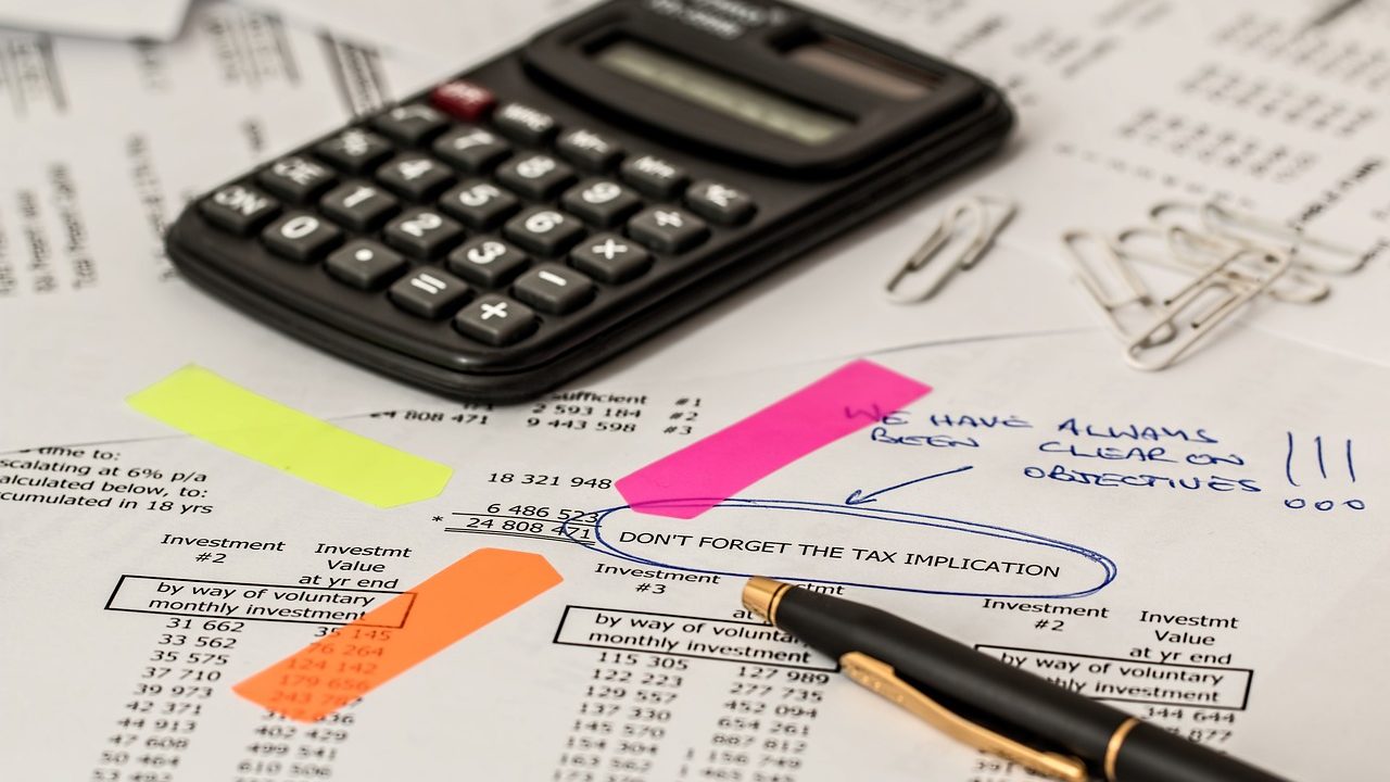 calculator resting on a stack of papers with numbers and figures
