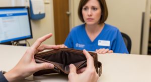 person opening their empty wallet in front of medical reception