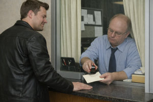admin clerk stamping an envelop while a young man grins