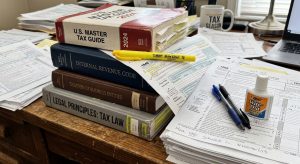 tax forms and books stacked on a desk